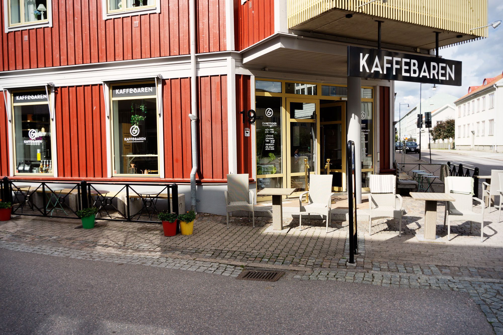 Rött hus med vita knutar, en Kaffebaren skylt i profilbokstäver, en uteservering på bottenvåningen